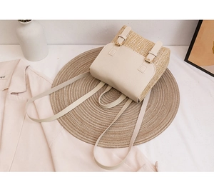 Flat lay view of a straw and beige leather mini backpack on a woven decorative mat