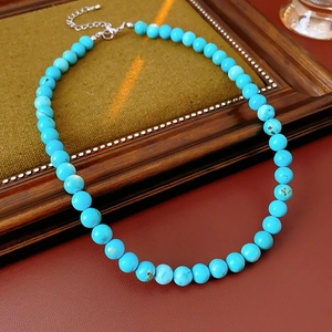 Detailed view of sky blue turquoise beads necklace on a vintage wooden frame display