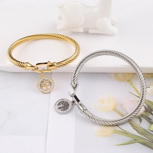 Detail of twisted cable bangles with Tree of Life pendants in gold and silver finish
