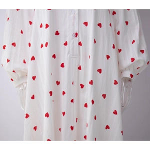 Détail de la robe en coton blanc avec imprimés cœurs rouges et texture rayée verticale