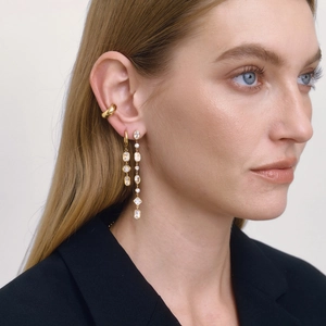 Macro shot of long gold geometric fringe earrings and ear cuff on a model in a black suit