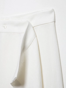 Detailed view of ivory twill fabric texture and single button closure on waist