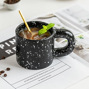 Chic black splatter ceramic mug with gold stirring spoon and white speckled ink design