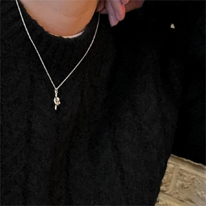 Close-up of minimalist silver knotted pendant necklace worn on a black sweater