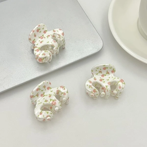 Three mini floral hair claws with pink flowers and green leaves on a white background