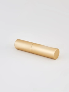 Detailed view of a cylindrical matte gold spray bottle with a smooth metallic texture