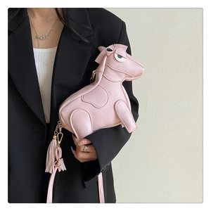 Close-up of pink horse-shaped leather crossbody bag with tassel on model in black blazer