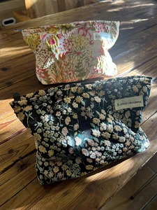 Detail view of floral embroidery on canvas makeup bags with zip closure and labels