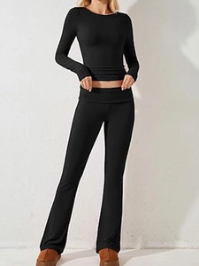 Dettaglio di un top nero a maniche lunghe e pantaloni a zampa su una modella donna