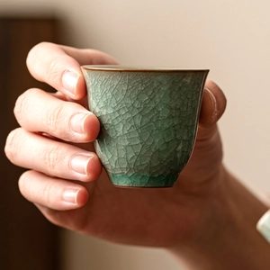 Ru Kiln ice-crack ceramic teacup with green glaze and hand-held close-up detail