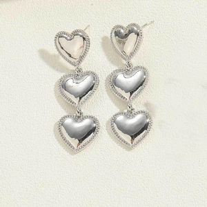 Detail of silver triple heart drop earrings with high-polish finish and beaded edges