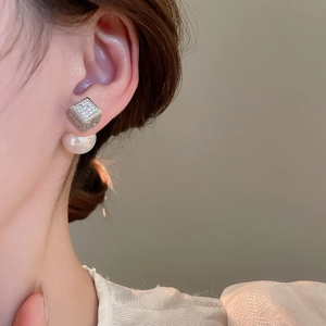 Detailed view of luxury square zircon stud earrings with pearl drop on a female model