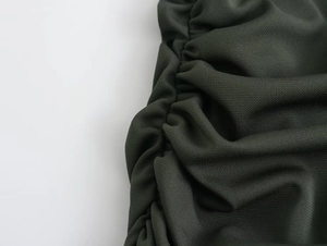Detail shot of forest green midi dress fabric showing ruched texture and pleated design