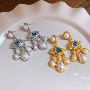 Detailed view of vintage evil eye drop earrings with pearls in gold and silver finish