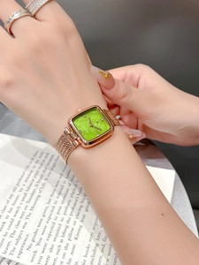 Elegant women's square watch with green dial and gold mesh strap on a model's wrist