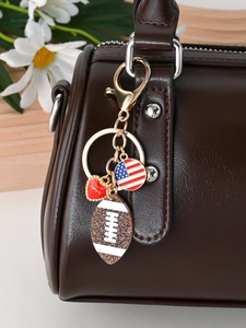 Close-up of golden American football keychain with red Love heart on brown leather bag