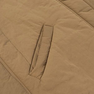 Close-up of khaki padded cotton jacket showing diagonal pocket and fine stitching detail