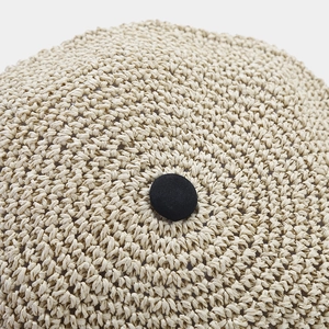 Close-up of beige straw woven hat top with a black fabric-covered decorative button