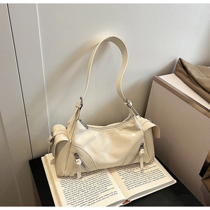 Detail view of the cream shoulder bag with glossy patent finish and zipper pockets