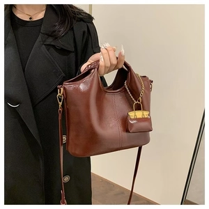 Macro view of vintage oil wax leather tote featuring sleek finish and chain charm detail