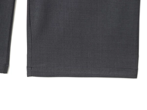 Detailed close-up showing the precise stitching and wool twill fabric of dark grey pants