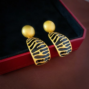 Vintage gold geometric earrings with black stripe enamel on a red jewelry box background