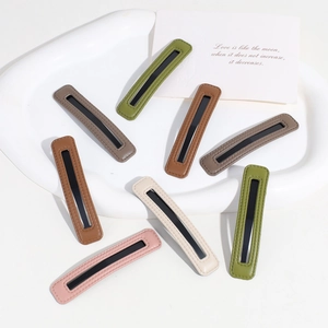 Detailed close-up of colorful PU leather hair clips in soft Morandi tones on a white tray