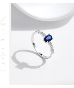 Macro detail of asymmetric silver ring with oval blue gemstone and white diamonds