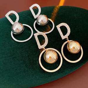 Detailed macro view of gold and silver letter D ball earrings with sparkling cubic zirconia