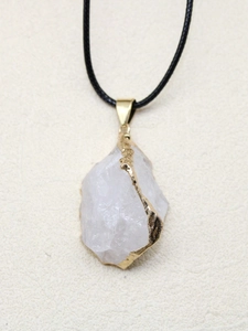 Gros plan d'un pendentif en cristal de roche brut avec bordure dorée galvanisée