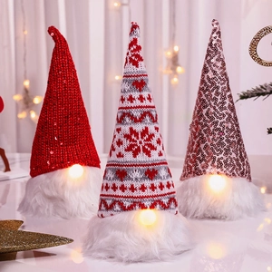 Three glowing Christmas gnomes with sequined hats and warm LED lights in a festive setting