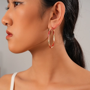 Close-up of golden and red enamel hoop earring worn by a model in a professional studio