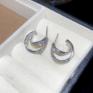 Detail of silver double-layered C-shape earrings with sparkling cubic zirconia inlay