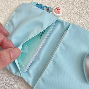 Detail of light blue nylon card holder with multiple slots and a white rabbit pendant
