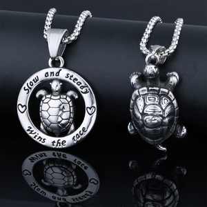 Detailed macro view of turtle pendants featuring the Slow and steady wins the race engraving