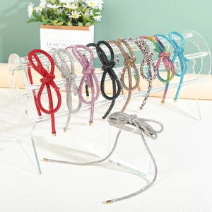 Sparkly rhinestone bow headbands with tassels in multiple colors on an acrylic stand