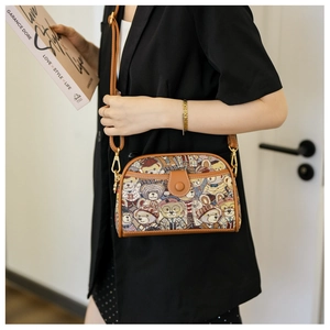 Detail view of canvas bear jacquard crossbody bag with brown leather trim on model