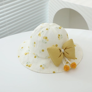 Close-up of baby sun hat featuring yellow cherry prints and a ginger yellow bow decoration
