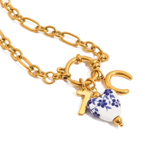 Detail of gold titanium steel necklace with heart ceramic pendant and IC letters
