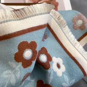 Detail of light blue floral scarf with brown patterns and beige fringe tassels