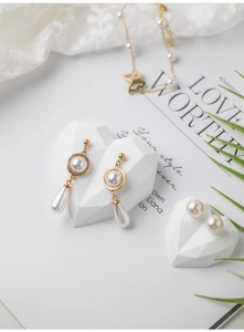 Detail of gold pearl jewelry set with heart stand and decorative magazine background