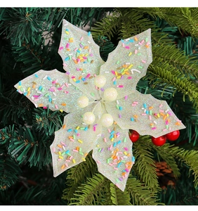 Detail of white glitter Christmas flower with colorful sequins on green tree branch