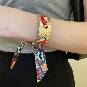 Detail of vintage gold textured cuff bracelet featuring an ethnic print silk scarf ribbon