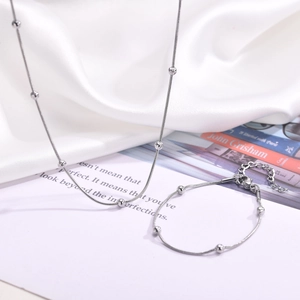 Detailed view of silver snake chain necklace and bracelet set with polished round beads