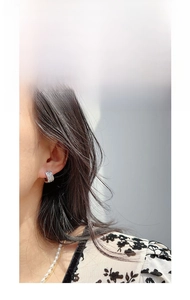 Detail of silver hoop earrings with zircon pavé worn by a model with a pearl necklace