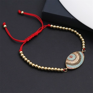 Detail of adjustable red woven evil eye bracelet with gold beads and colorful zircon stones