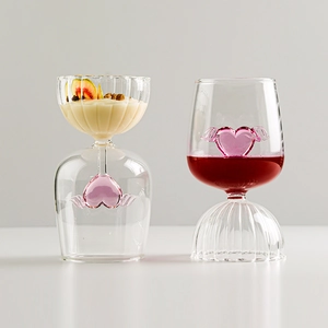 Creative heart-winged glass wine goblets set with pink accents and dessert content