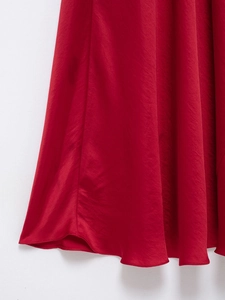 Détail de la texture en satin rouge avec un drapé élégant et fluide sur cette robe