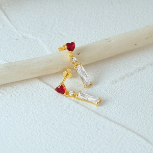Macro shot of gold S925 silver earrings with red heart stones and crystal zircon details