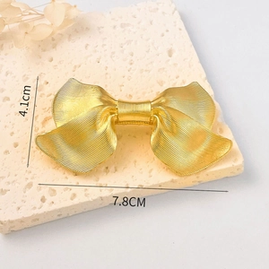 Detailed view of a textured golden alloy bow hair clip with 7.8cm and 4.1cm measurements